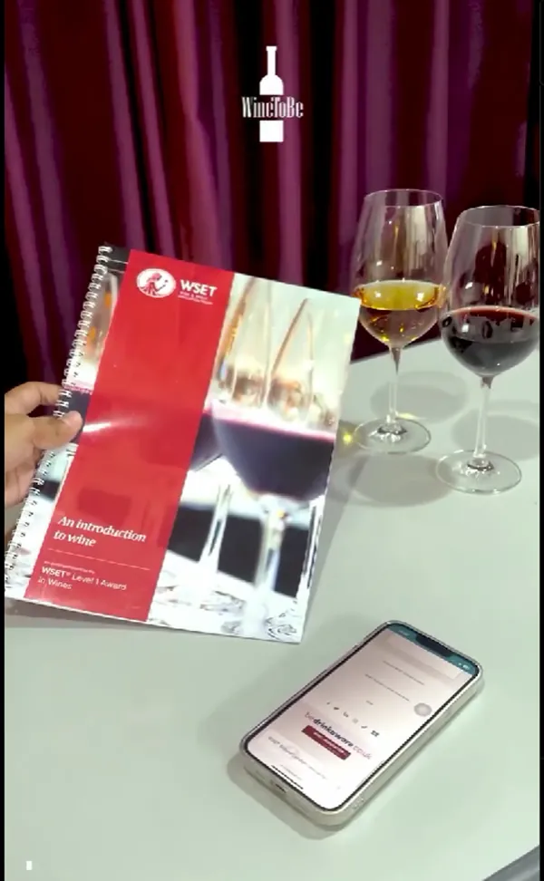 Buku belajar WSET Level 1, An Introduction to Wine, di meja tasting dengan dua gelas wine